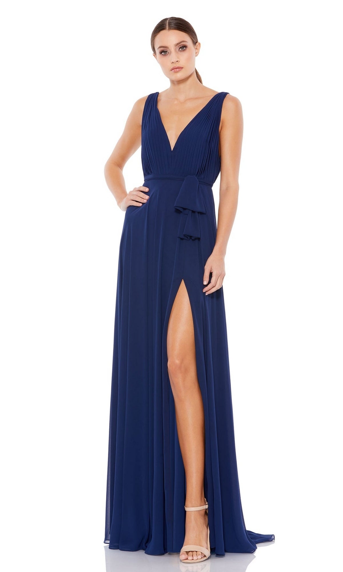 A woman models the Mac Duggal 55283 Midnight Blue Long Formal Dress featuring a sleeveless design, deep V-neckline, high slit, and a-line skirt with neutral heels against a plain white background.